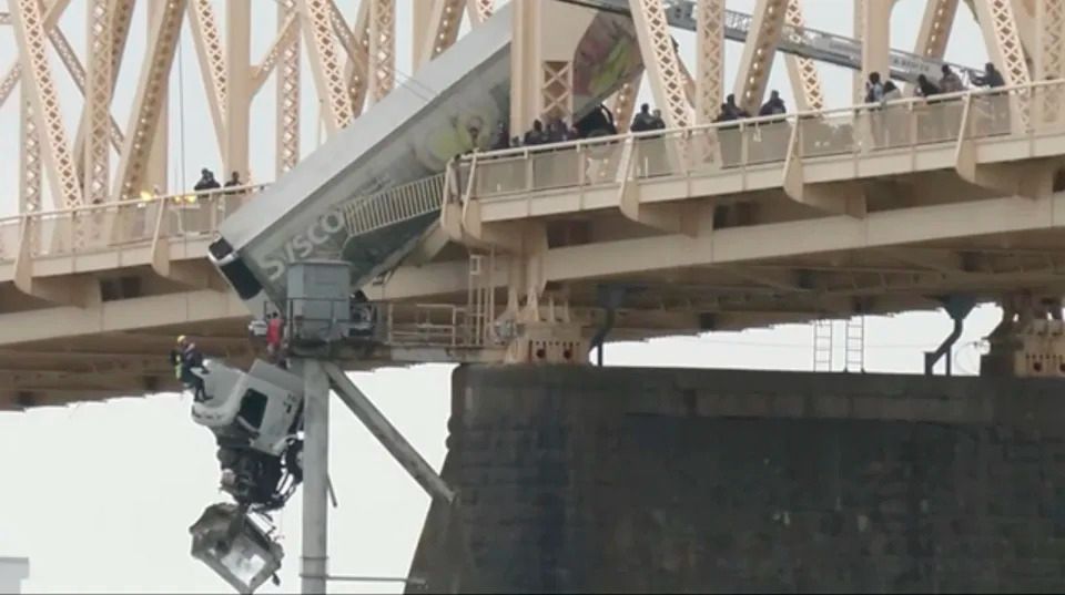 Louisville emergency crews rescue the driver of semitruck that is dangling off the Clark Memorial Bridge over the Ohio River on Friday, March 1, 2024 in Louisville, Ky. The driver was pulled to safety by firefighters following the three-vehicle crash on the bridge connecting Louisville, Kentucky to southern Indiana. (WDRB via AP