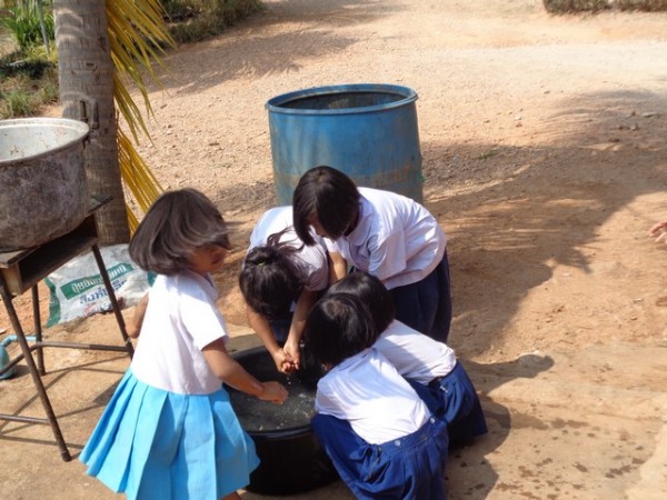 queuing up to wash their hands in a bucket of water